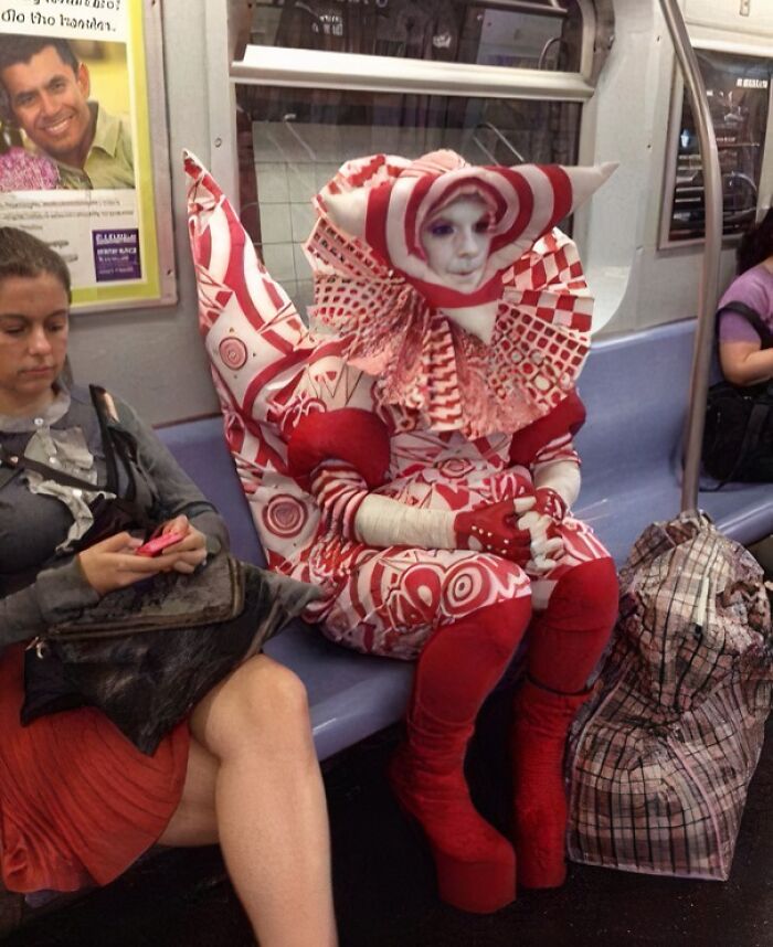 Person in an elaborate red and white costume sitting on a NYC subway, highlighting weird moments on the subway.