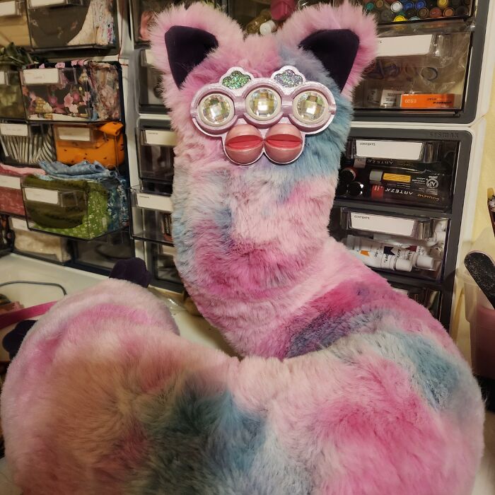 Plush toy with pastel pink, blue, and purple fur, unique kaleidoscope-style glasses, representing weird popular subreddits.
