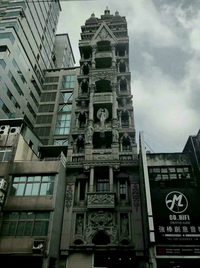 A highly ornate, narrow building with numerous statues and intricate details, suggesting a villain's lair for an evil mastermind.