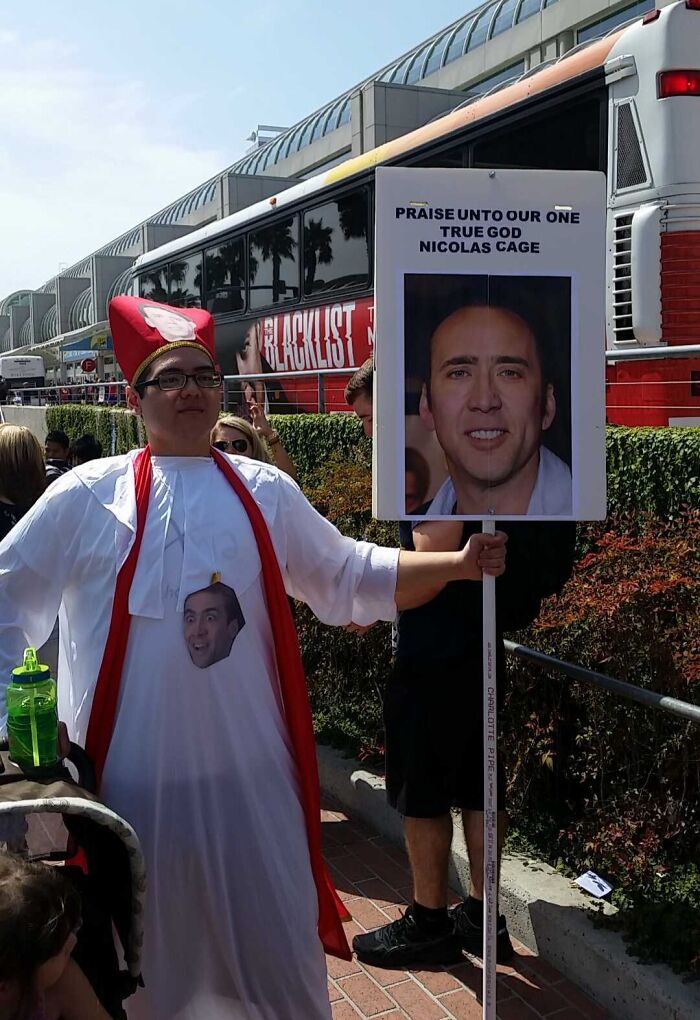 Person dressed in a Nicolas Cage costume holding a sign, representing one of the weirdest popular subreddits.