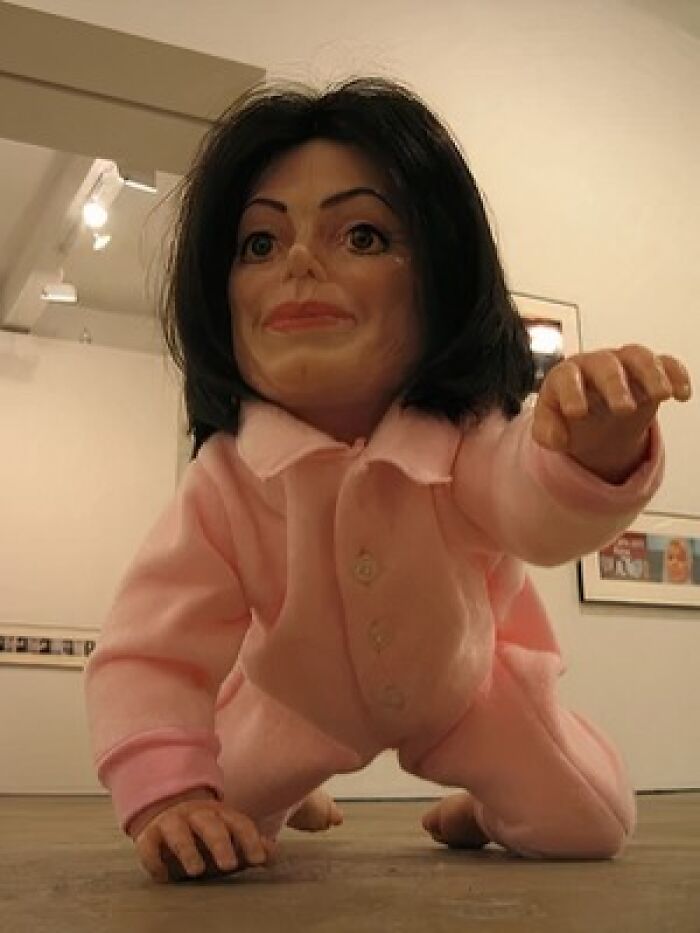 Creepy doll with human-like face wearing pink pajamas crawling on floor, representing weird subreddits very popular online.
