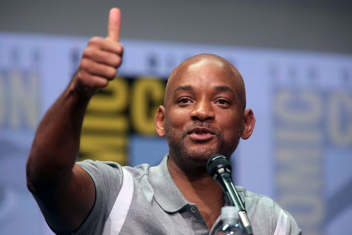 Actor speaking into a microphone with a thumbs up gesture, illustrating celebrity lifestyle and custom mobile mansion.