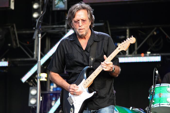 Man playing electric guitar on stage during a live concert performance under stage lights and equipment.