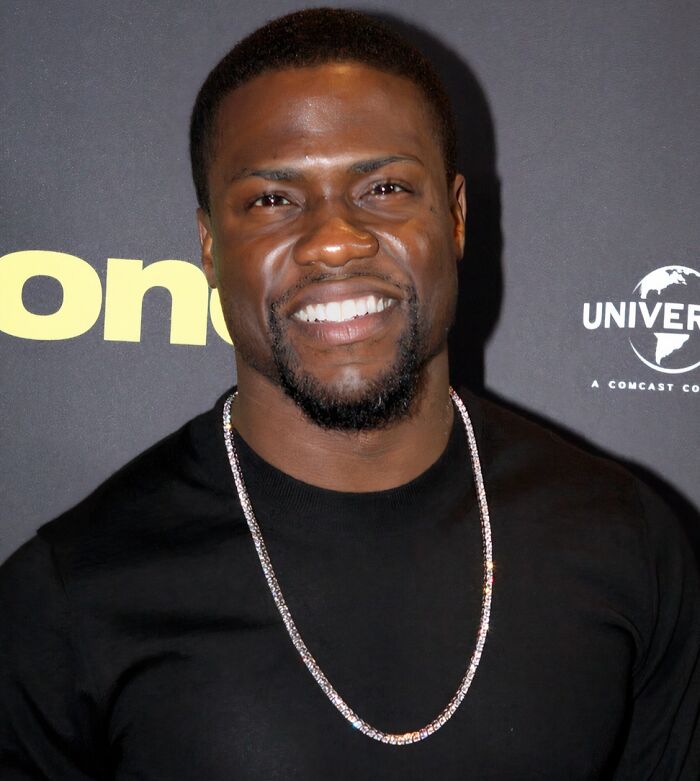 Man smiling at a media event wearing a black shirt and chain, related to custom 2.5 million mobile mansion requests.