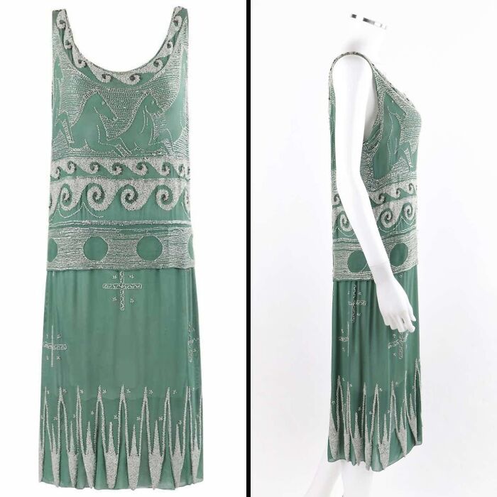 Green beaded historical garment with wave and animal motifs displayed on a mannequin, showcasing vintage fashion design.