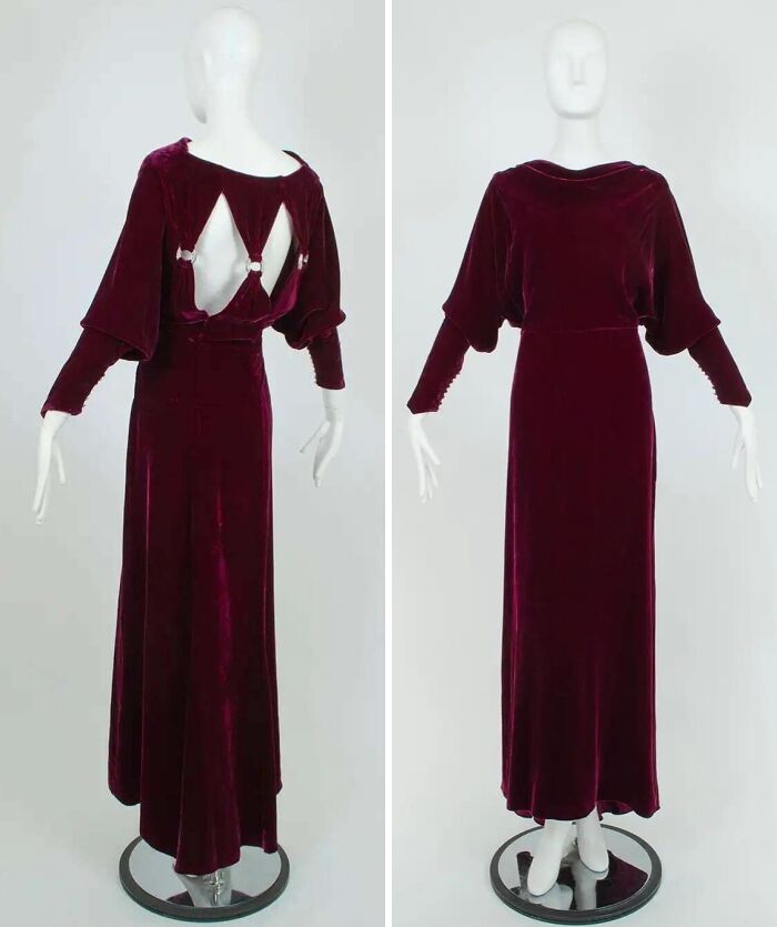 Vintage deep red velvet historical garment with long sleeves and unique open back design on mannequin.
