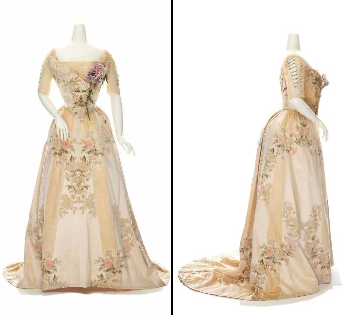 Vintage historical garment with floral embroidery and a long train displayed on a mannequin from front and side views.