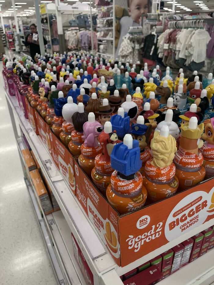 Rows of Good2Grow drinks with character tops in a store aisle, a prime example of consumerism and 400% price difference.