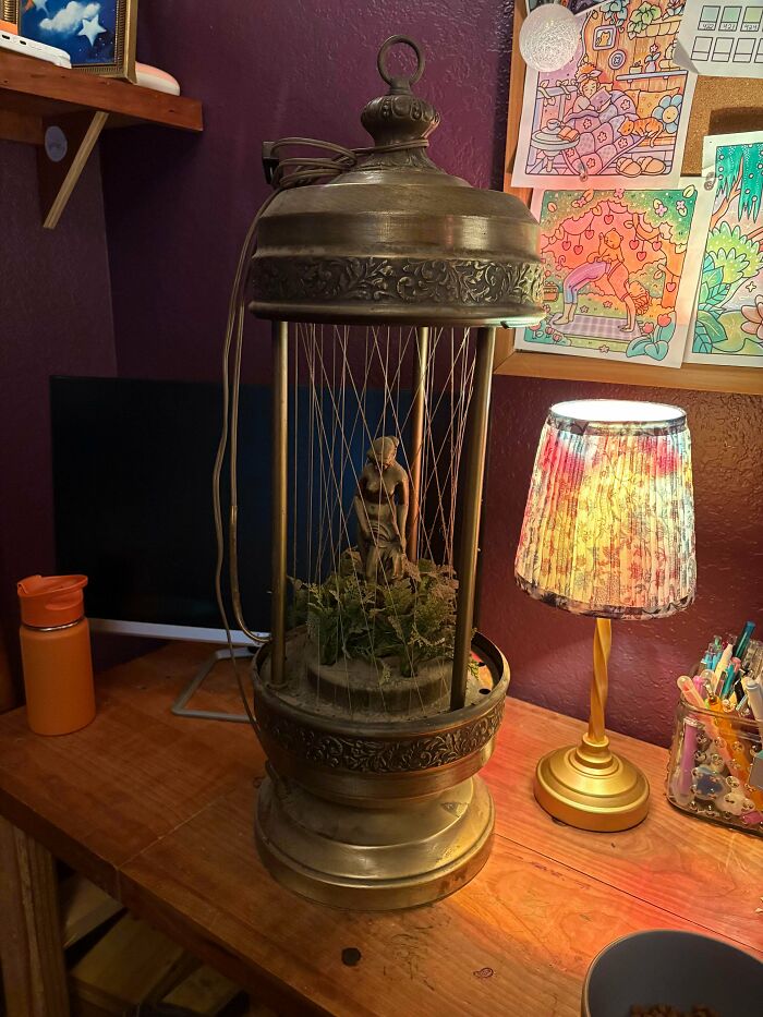 An ornate vintage rain lamp with a statue inside, a unique thrift store jackpot.