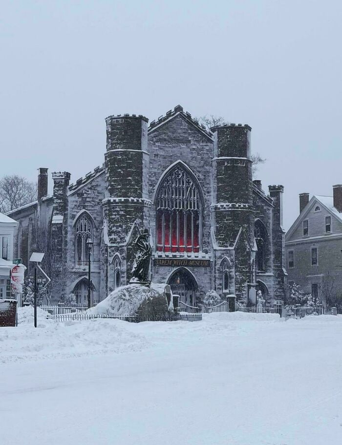 A snowy scene featuring a gothic-style building with a statue in front, possibly for an evil mastermind.