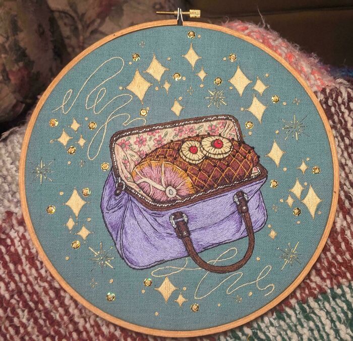 A detailed embroidery creation showing a vintage suitcase with snacks and sparkling elements.