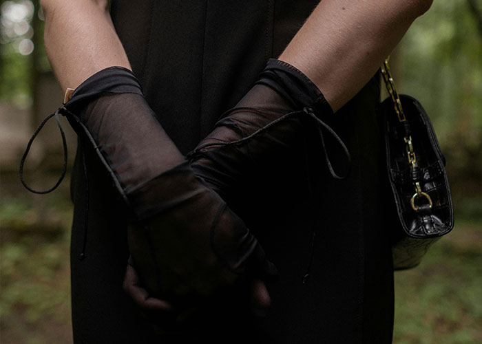 Person wearing black dress and sheer gloves holding hands in front, symbolizing teen and stepmom tension on wedding day.