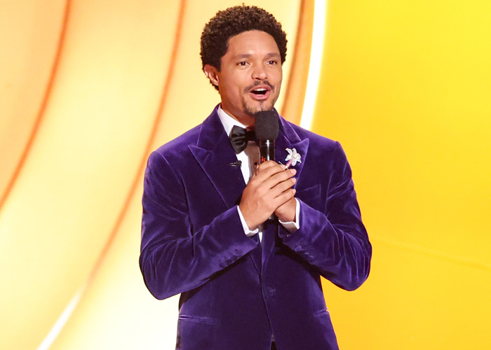 Trevor Noah speaking on stage in a purple velvet jacket, illustrating body language expert analysis of tense behavior. Trevor Noah speaking on stage in a purple velvet jacket, illustrating body language expert analysis of tense behavior.