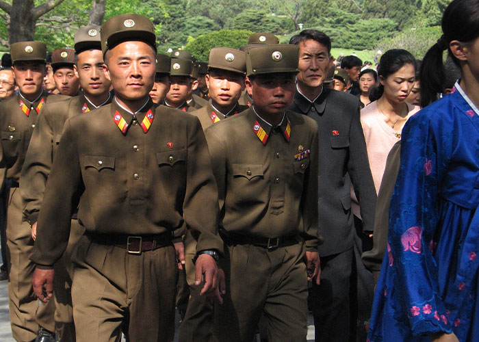 North Korean soldiers and civilians walking outdoors, illustrating public executions of citizens caught watching Squid Game.
