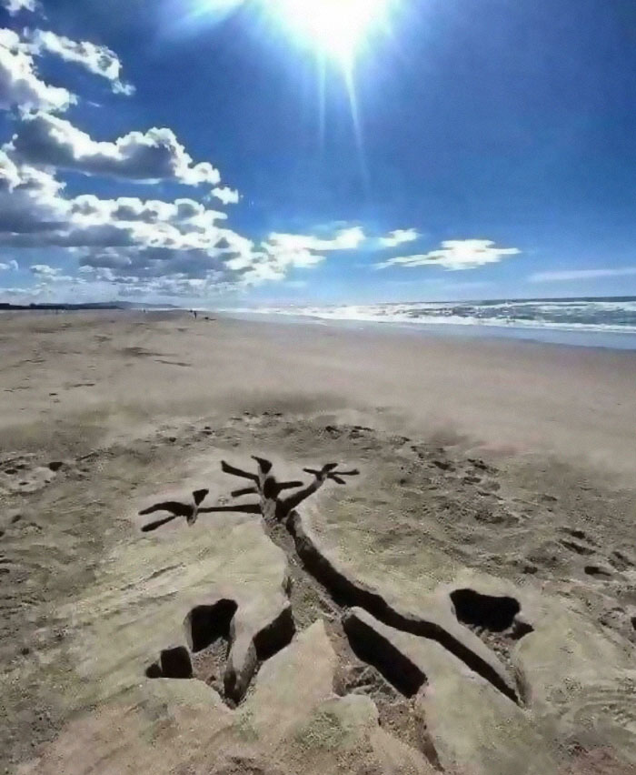 Sand art on a sunny beach with bright sky and clouds, evoking nostalgic pics and references by the ocean shore.