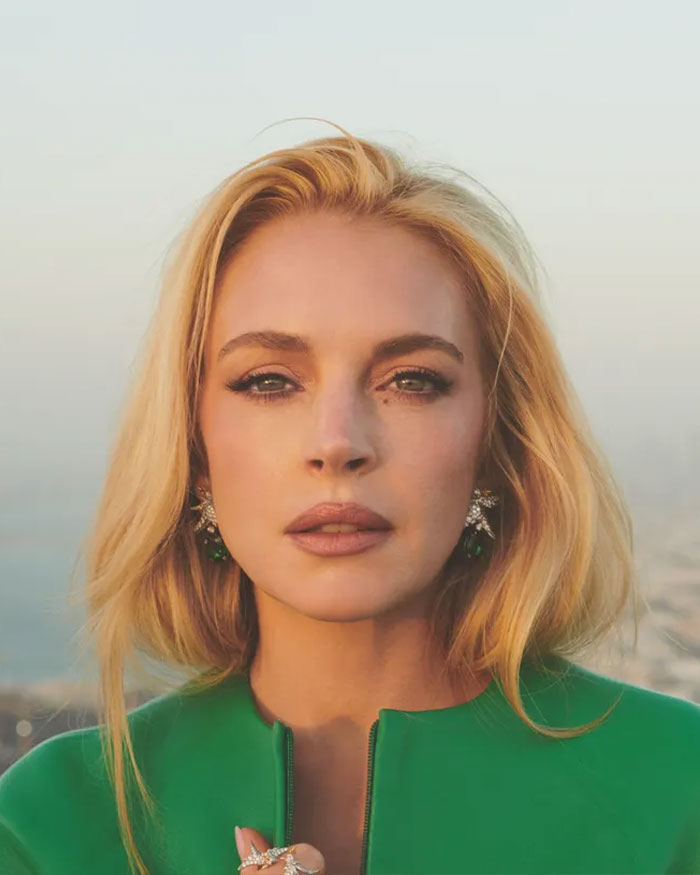 Lindsay Lohan in a green outfit, looking thoughtful while exposing the dark side of growing up famous.