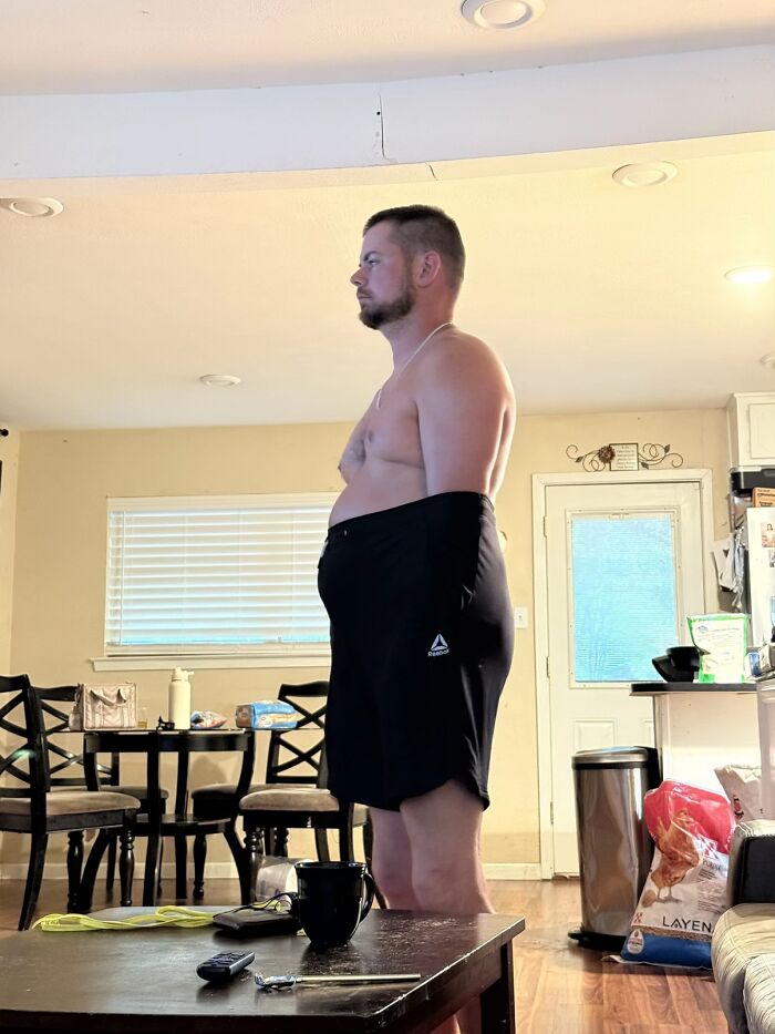 Man standing awkwardly indoors with shirt off and shorts pulled up high, displaying hilariously awkward body language.