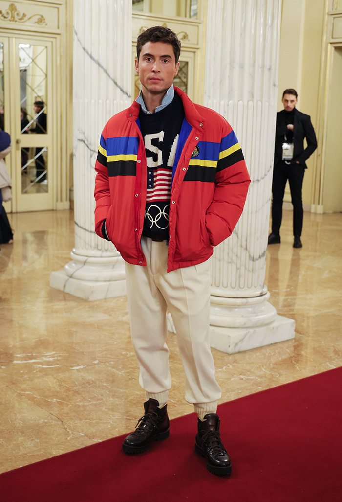 Young man on red carpet wearing colorful jacket and white pants, featured in worst dressed celebs Olympics 2026 Milan event.