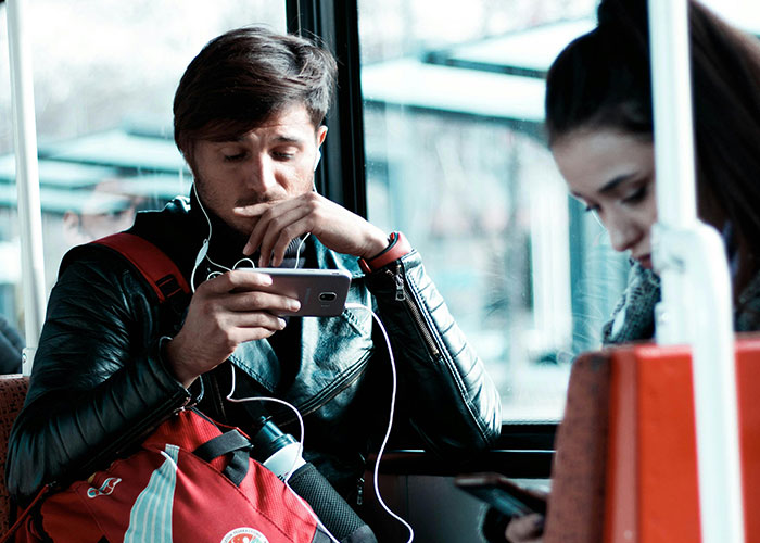 Young man and woman on public transport using mobile phones, illustrating modern countries and smart everyday habits.