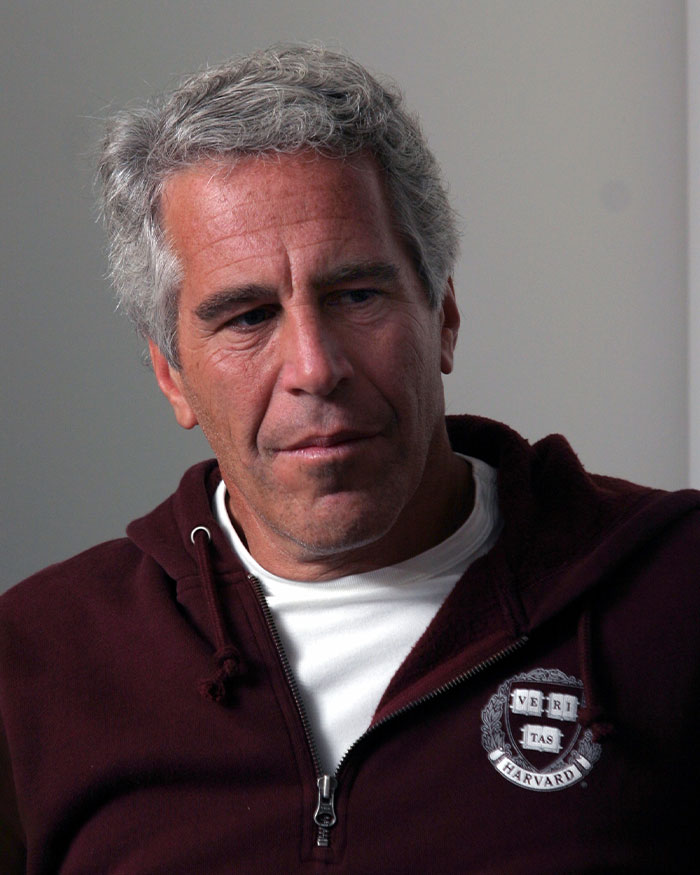 Man wearing a maroon Harvard hoodie, appearing thoughtful in an indoor setting related to mobile game players and Pok&eacute;mon controversy.
