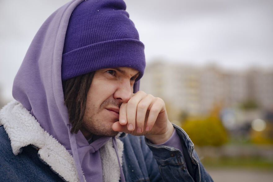 Young man in purple beanie and hoodie showing frustration outdoors, representing common pet peeves that divide a room.