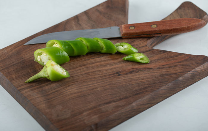 Green chili sliced on a wooden cutting board with a kitchen knife, illustrating quick fixes that turned out to be genius.
