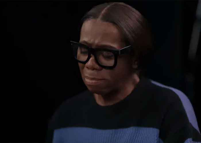 ANTM star J Alexander wearing large glasses, looking emotional while discussing his stroke and Tyra Banks' response.