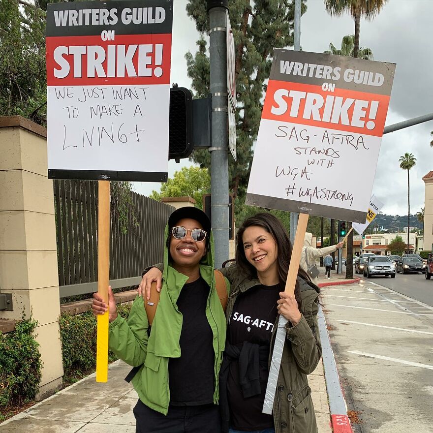 Two smiling writers holding strike signs outdoors on a street, highlighting the Oscars 2026 update on date and time. Two smiling writers holding strike signs outdoors on a street, highlighting the Oscars 2026 update on date and time.