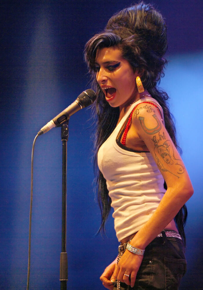 Singer with tattoos performing on stage at microphone, representing celebrities falsely accused of crimes.