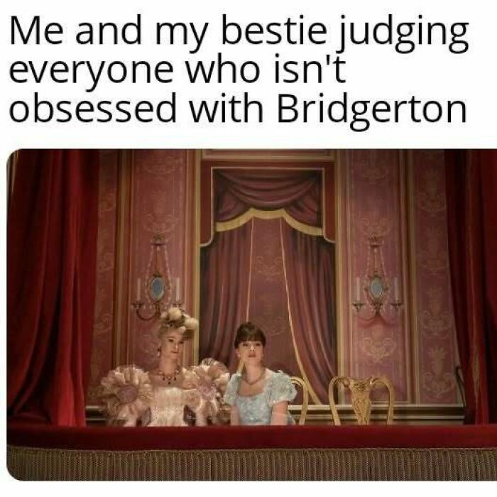 Two women in Bridgerton costumes sitting in a theater box, judging those not obsessed with Bridgerton series.
