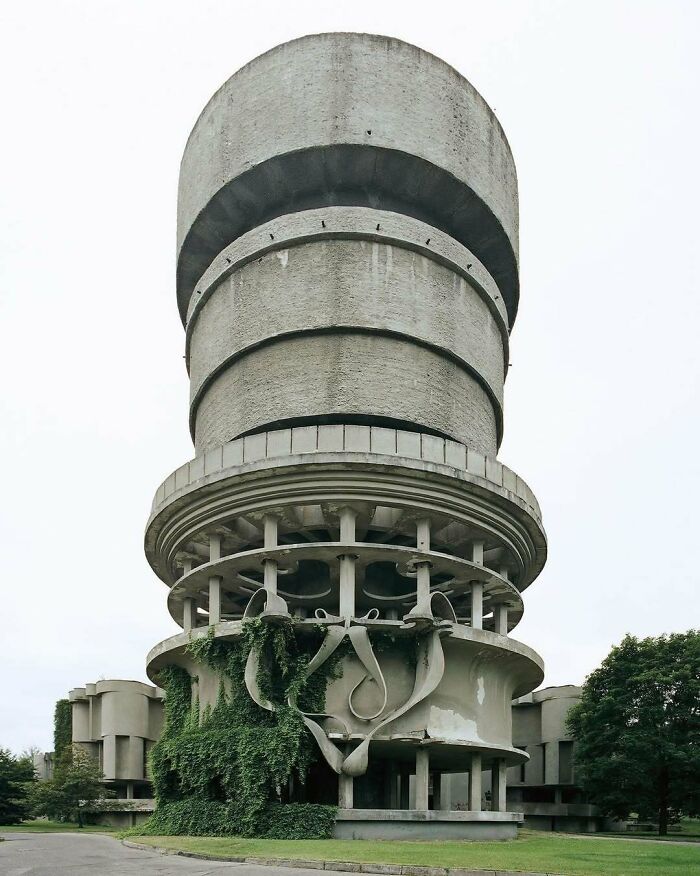 Unique interesting building with concrete spiral structure partially covered in ivy in an overgrown abandoned setting