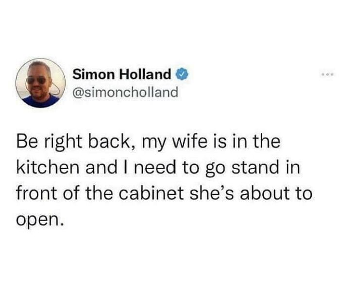 Tweet text about marriage humor where husband says he needs to stand in front of the kitchen cabinet wife is about to open.