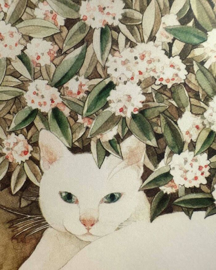 White cat painting surrounded by flowers and leaves, showcasing cats as a favorite art subject throughout the years.