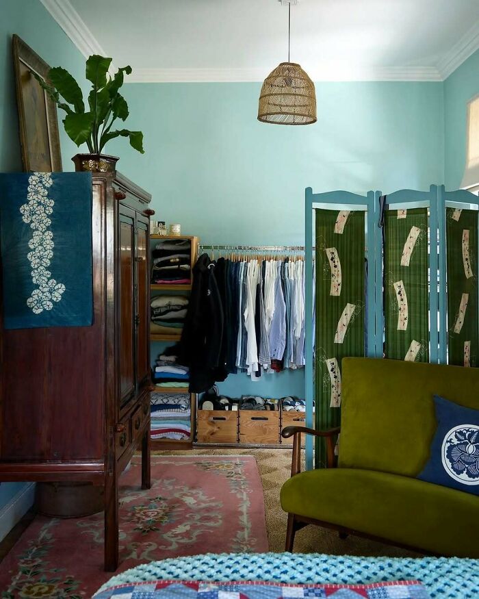 Bold and beautiful interiors featuring a vibrant green sofa, wooden wardrobe, patterned room divider, and light blue walls.