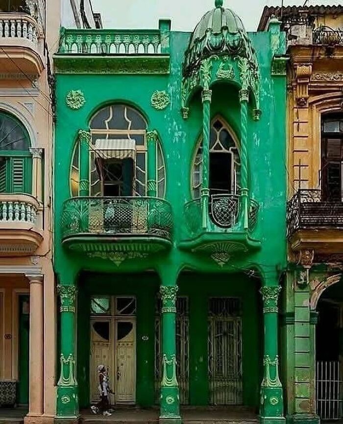 Green ornate architectural structure with decorative balconies and columns showcasing unique creativity and design.
