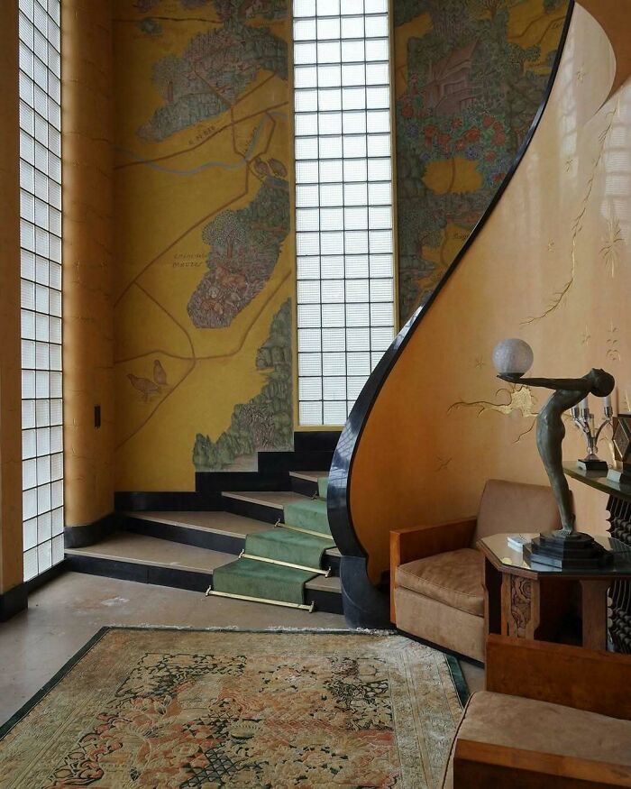 Bold and beautiful interiors featuring a curved staircase, vintage furniture, and detailed wall artwork in a stylish living space