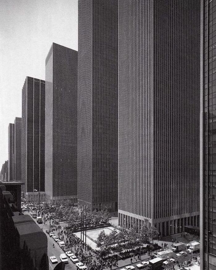 Black and white image of tall architectural structures and busy street showcasing humanity's creativity in architecture.