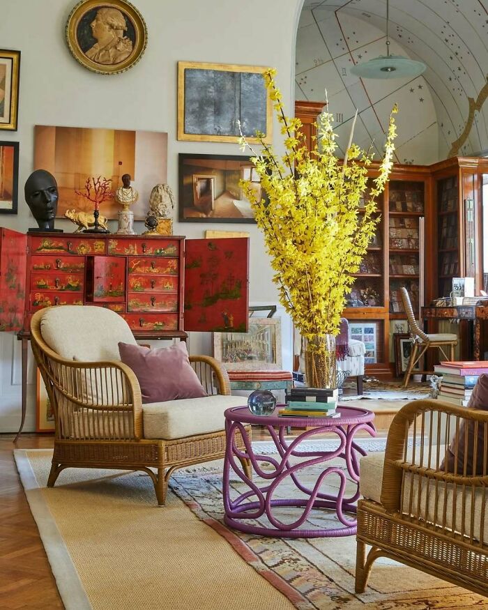 Bold and beautiful interiors featuring wicker chairs, vibrant yellow floral arrangement, and eclectic vintage decor elements.