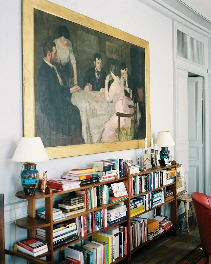Bold and beautiful interiors featuring an elegant bookshelf, classic painting, and vintage decor in a stylish living space.