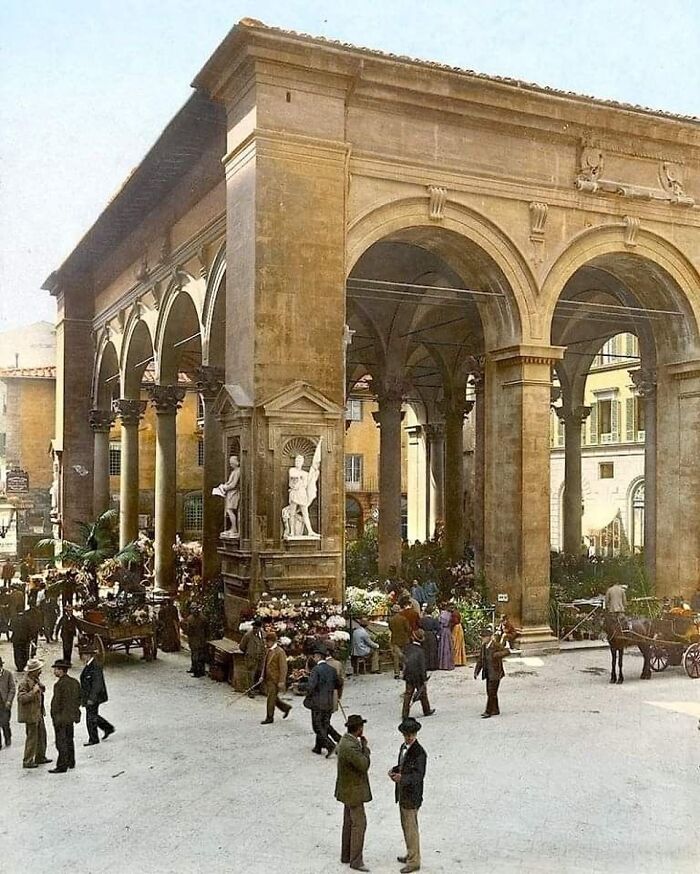 Historic architectural structure with large arches and columns in a bustling public square showcasing human creativity.