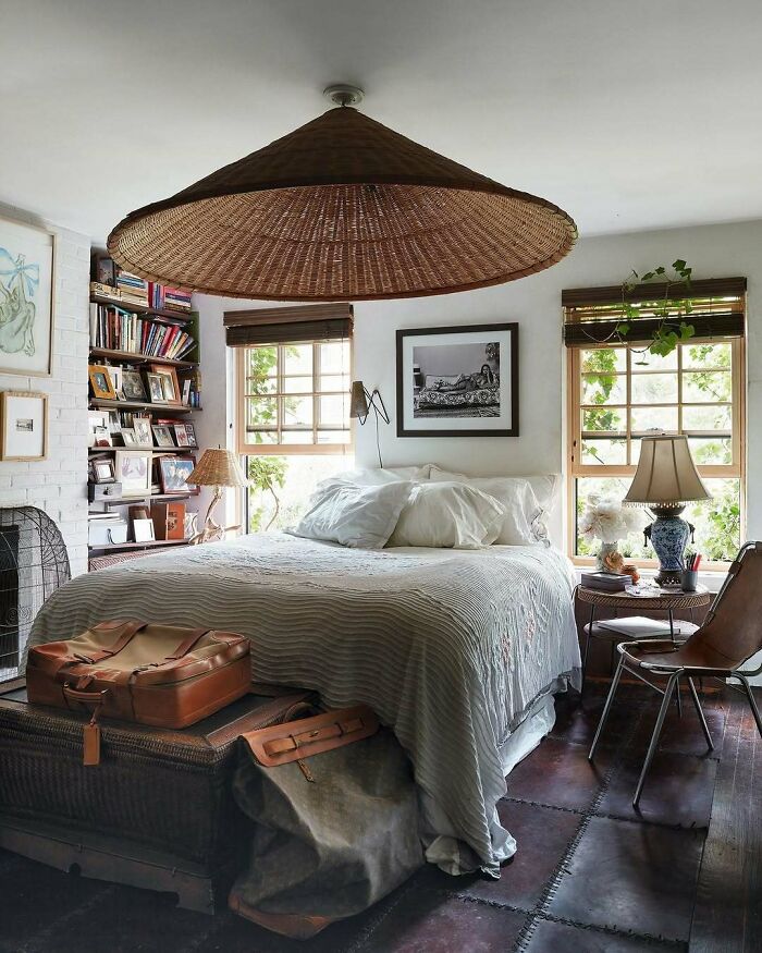 Cozy bedroom with bold and beautiful interiors featuring a large wicker lampshade and natural light from windows.