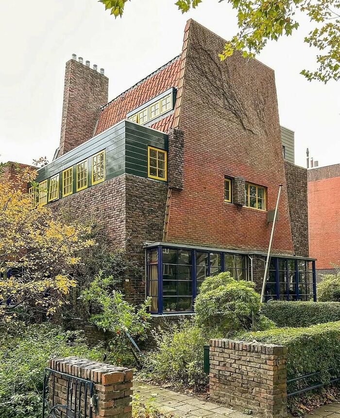 Unique architectural structure with brick facade, large windows, and lush greenery showcasing humanity's creativity and design skills.