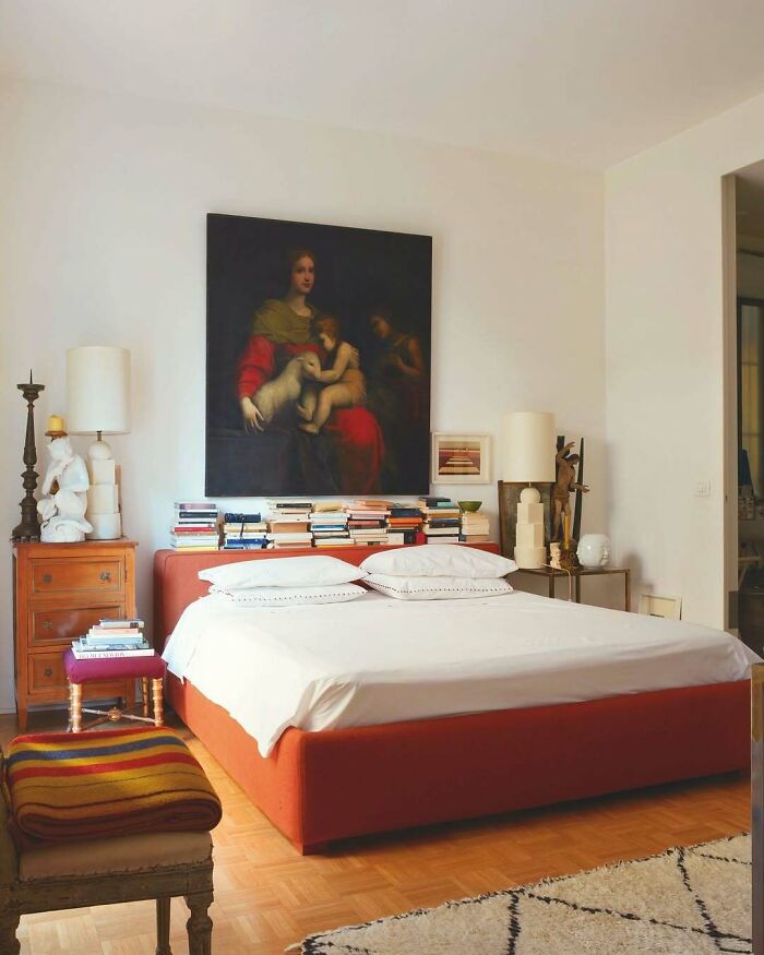 Bold and beautiful interior featuring a red bed, classic artwork, and eclectic decor in a cozy bedroom setting.