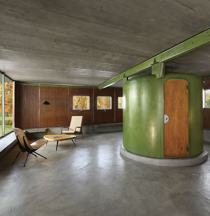 Modern architectural structures featuring minimalist design with concrete floors and unique green cylindrical room.