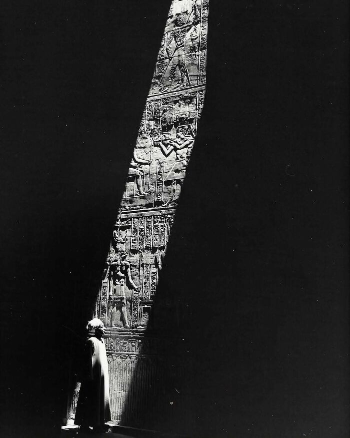 Person standing in shadowed ancient architectural structure with intricate carvings showcasing humanity's creativity.
