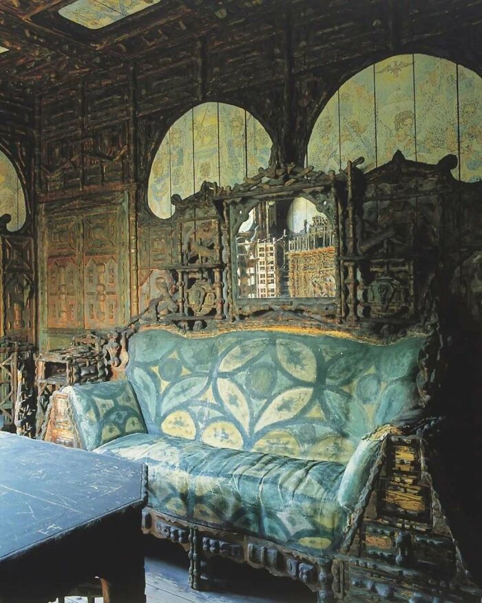 Ornate bold and beautiful interior featuring an artistic patterned sofa and intricate wooden wall paneling with mirror accents.