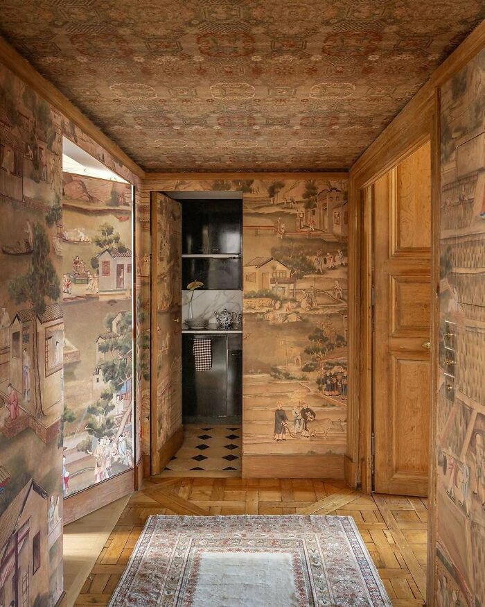 Hallway with bold and beautiful interiors featuring detailed wall murals, wooden doors, and patterned ceiling design.