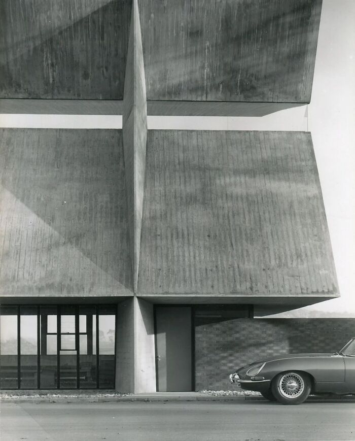 Modern architectural structure with bold geometric concrete shapes and a classic car parked nearby, showcasing creativity.