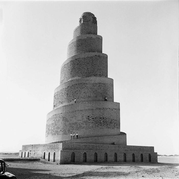 Spiral brick architectural structure with people standing on different levels, showcasing amazing architectural creativity.