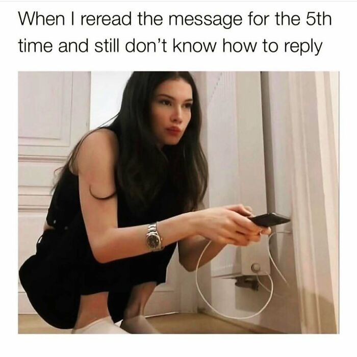 Young woman crouching on the floor, holding a phone and looking confused, from cute and wholesome posts for girlies.